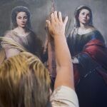 Una mujer invidente palpa con su mano una de las pinturas de la exposición