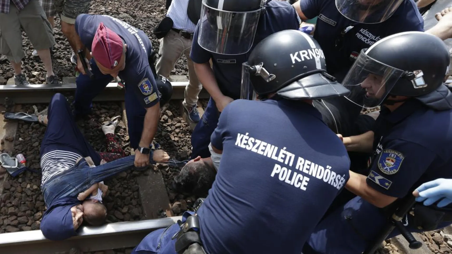Unos refugiados son detenidos cuando trataban de subir a un tren en Hungría.