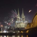 Fuegos artificiales iluminan la catedral de Colonia (Alemania) junto al río Rin durante las celebraciones de Año Nuevo