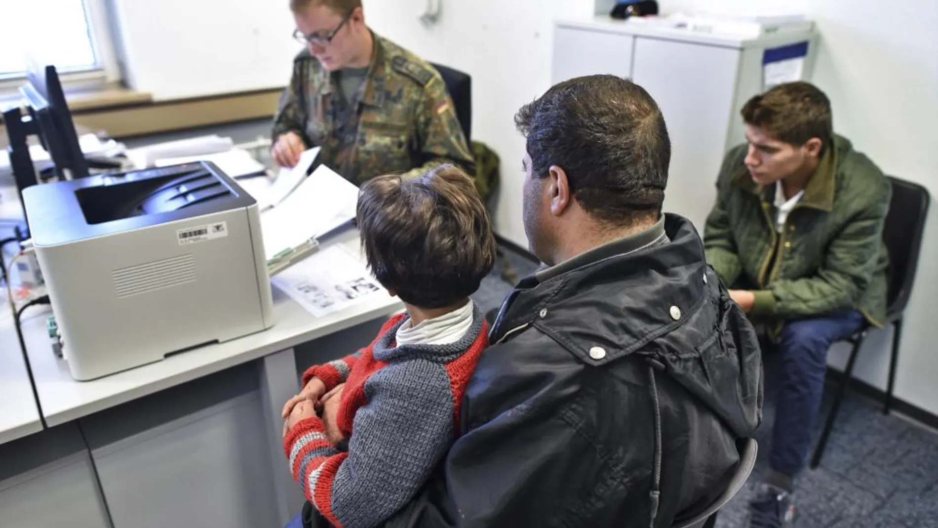 Un soldado entrega documentos a una familia de refugiados en la oficina de registro de Heidelberg (Alemania)