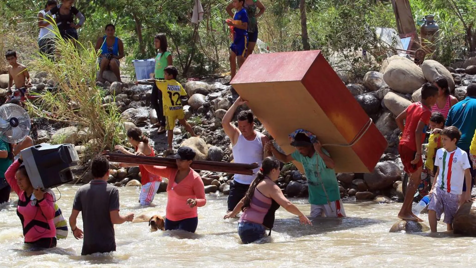 Cientos de colombianos cargan sus pertenencias por el río Táchira desde Venezuela hacia el sector La Parada (Colombia)