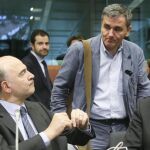 El comisario de Asuntos Económicos, Pierre Moscovici (i), conversa con el ministro giego de Finanzas, Euclides Tsakalotos (c) y el vicepresidente de la CE para el Euro, Valdis Dombrovskis (d).
