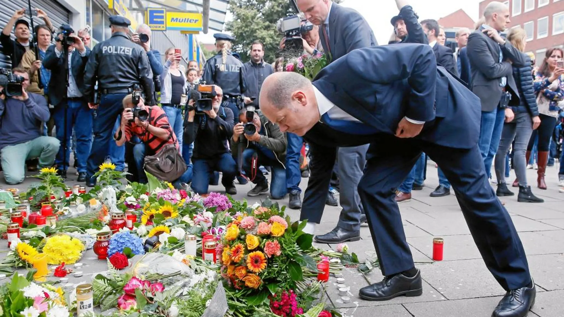 El alcalde de Hamburgo Olaf Scholz deposita flores frente al supermercado donde se produjo el ataque