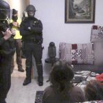 Agentes de las unidades especiales de intervención de la Guardia Civil vigilan a uno de los detenidos de la célula yihadista de captación del Daesh tras irrumpir en su domicilio en la madrugada del sábado