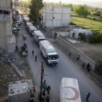 Un comboy de camiones de la Media Luna Roja y de Naciones Unidas entre en un suburbio de Damasco