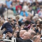 El Papa Francisco besa a un bebé a su llegada a la audiencia general de los miércoles en la Plaza de San Pedro en el Vaticano hoy