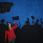 Un miembro del movimiento ciudadano "Damn the troika"pintando en un mural en Lisboa , en el que se pide la dimisión del presidente del gonierno portugués y llama a la participación ciudadana a manifestarse el próximo 2 de octubre.