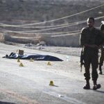 Dos soldados israelíes cusatodian el cadáver de un hombre en el lugar del ataque