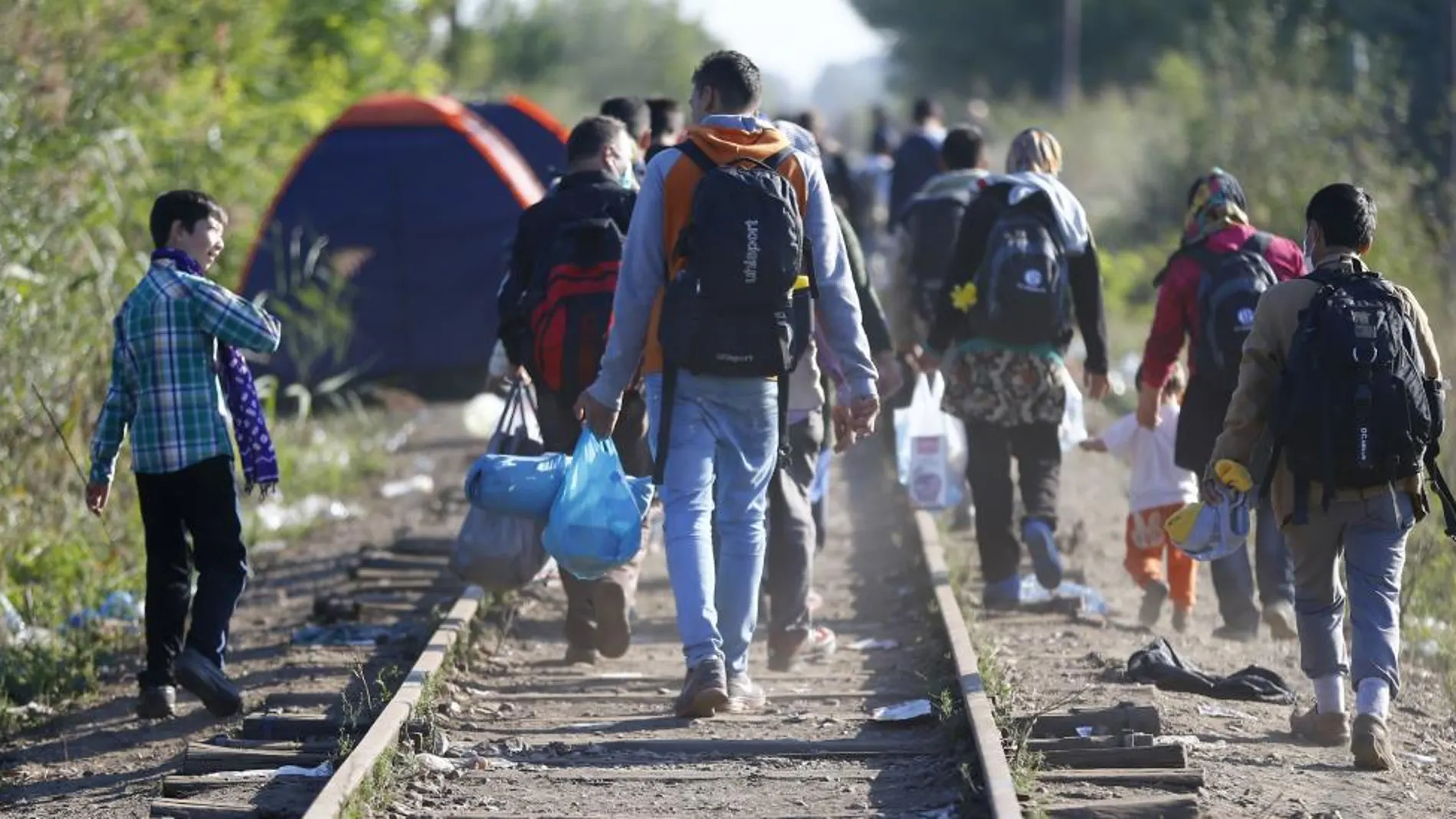 Refugiados caminan junto a las vías del tren en la frontera entre Serbia y Hungría.