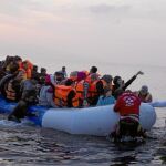 Un grupo de voluntarios ayuda a alcanzar la costa a un patera abarrotada de migrantes ayer en la isla griega de Lesbos