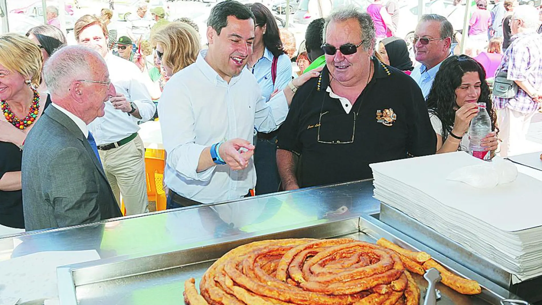 El presidente del PP-A, Juanma Moreno, en un puesto de churros durante su visita al mercadillo de Roquetas de Mar