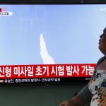 Una surcoreana pasa por delante de una pantalla durante la transmisión televisada del lanzamiento por parte de Corea del Norte de un proyectil que podría ser un misil balístico