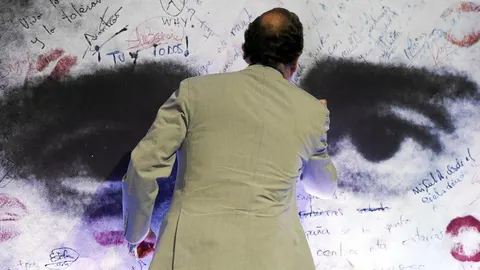 El presidente del Gobierno, Mariano Rajoy, ayer en Bilbao, escribe en el mural de Miguel Ángel Blanco en la escuela de verano de NNGG del PP