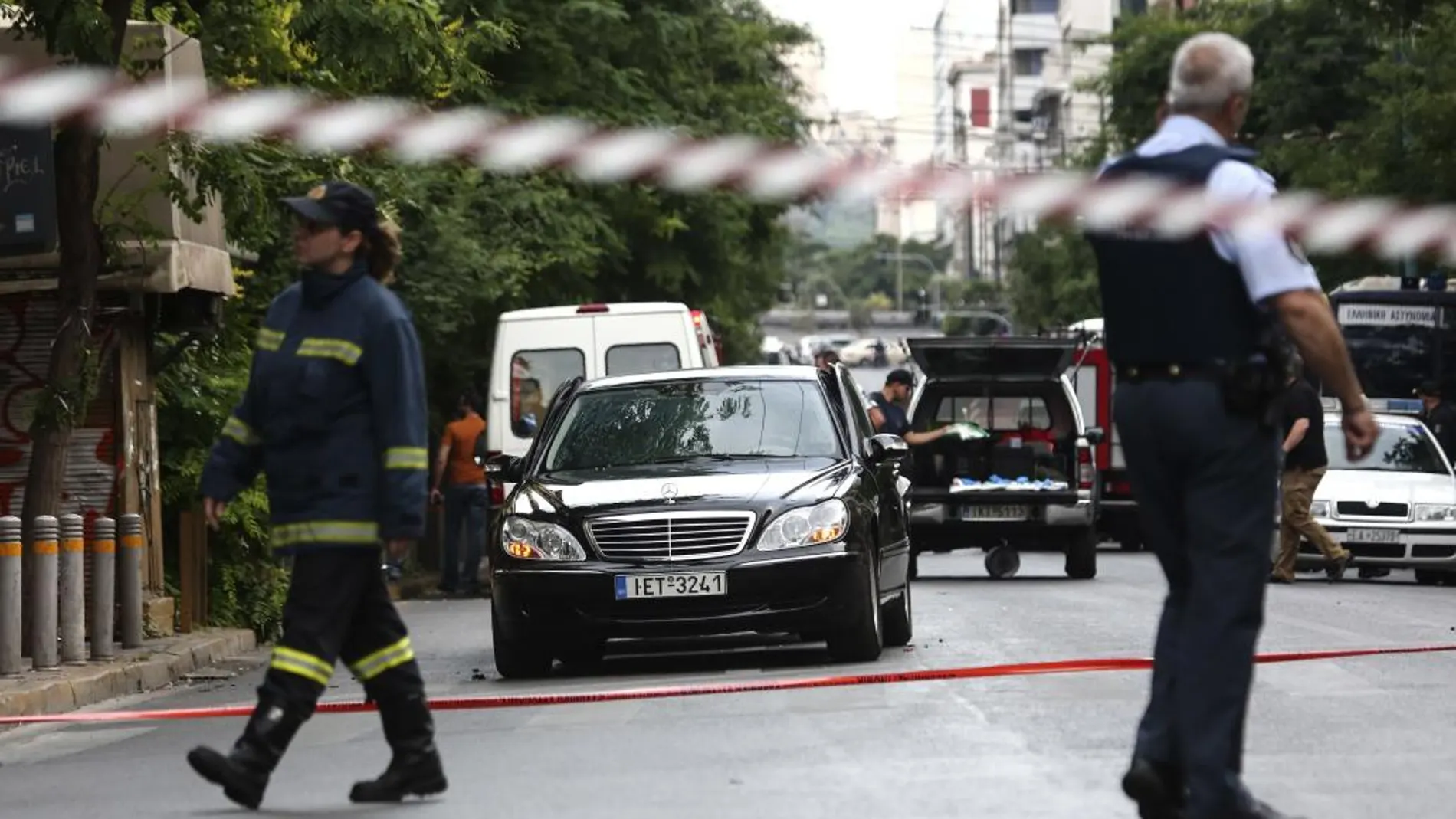 Miembros de los servicios de emergencias junto al coche del ex primer ministro griego Lucas Papademos.