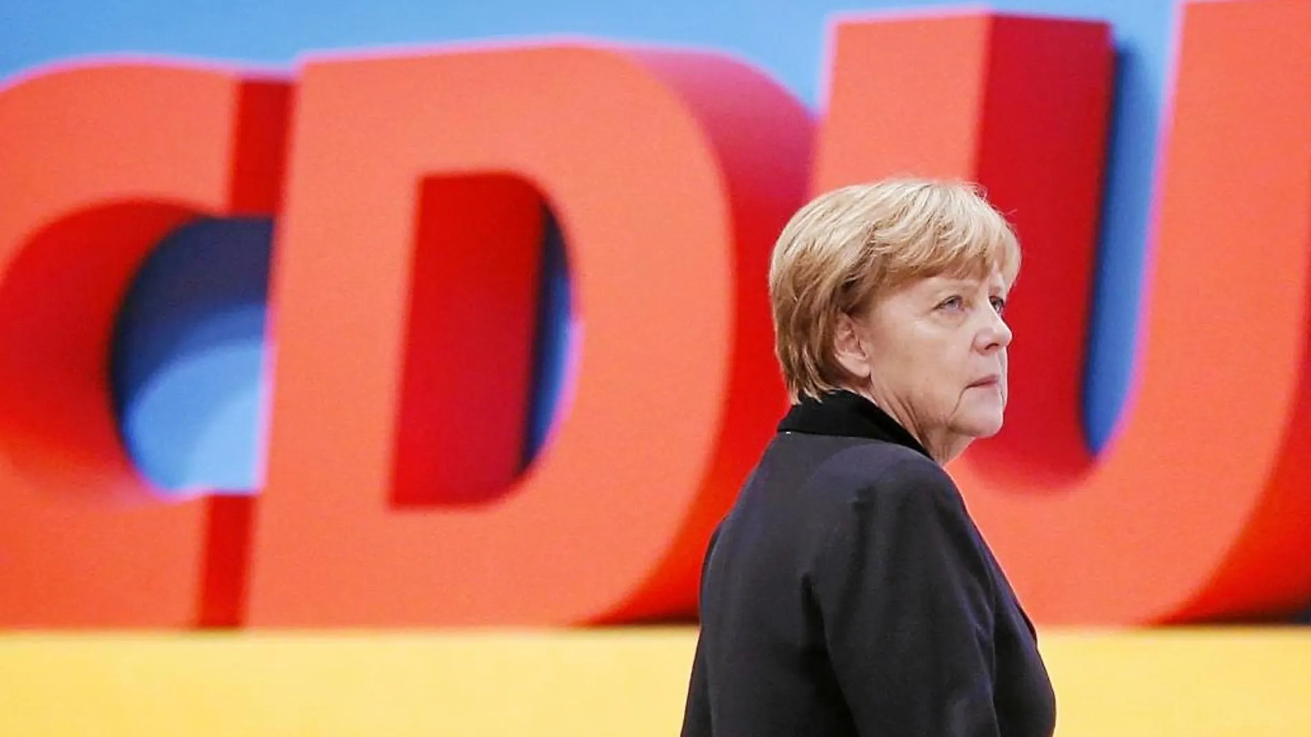 Angela Merkel junto a las siglas de su partido, ayer antes de su discurso