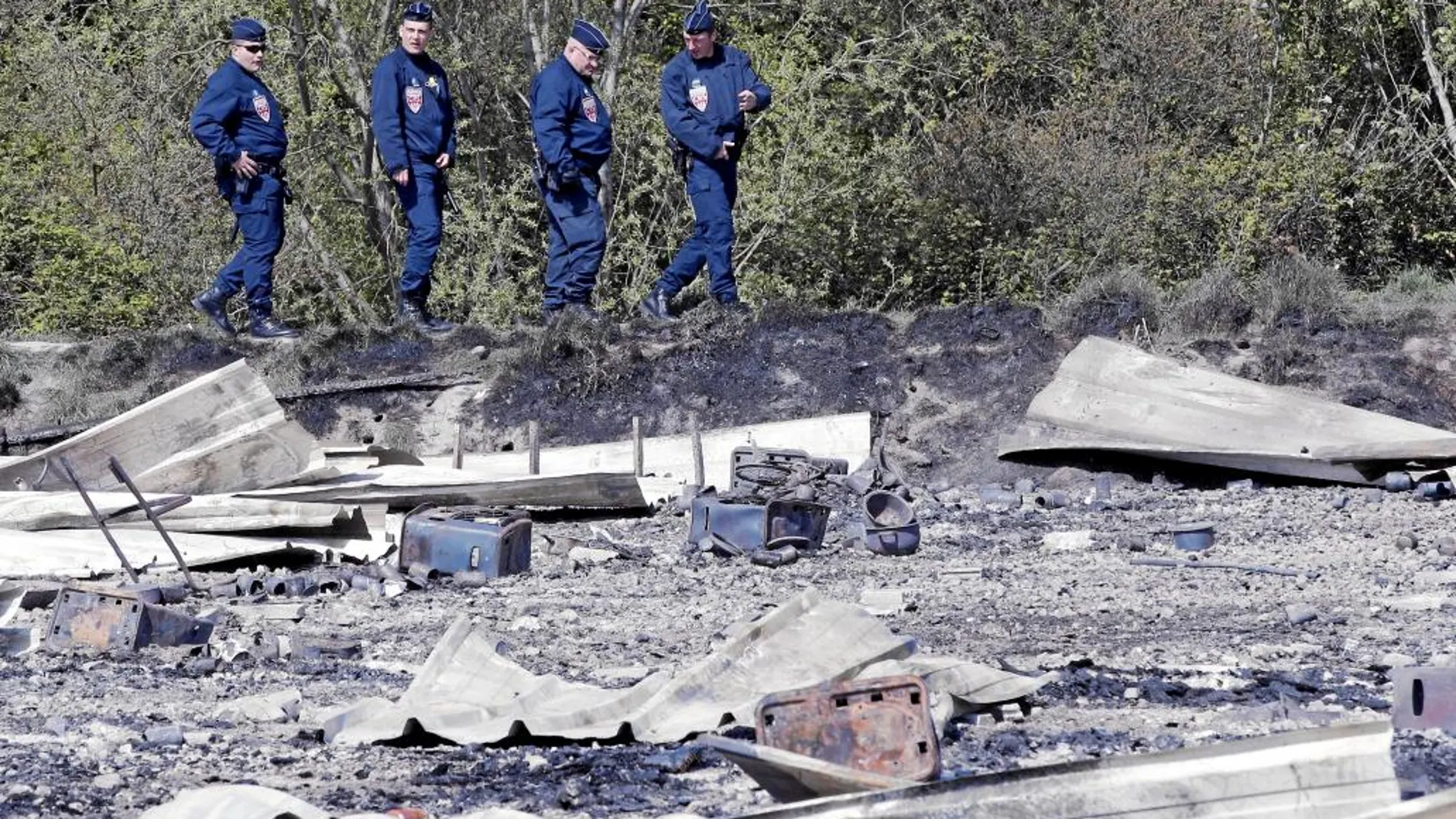 Una patrulla policial inspecciona los restos del incendio del campamento de Grande-Synthe