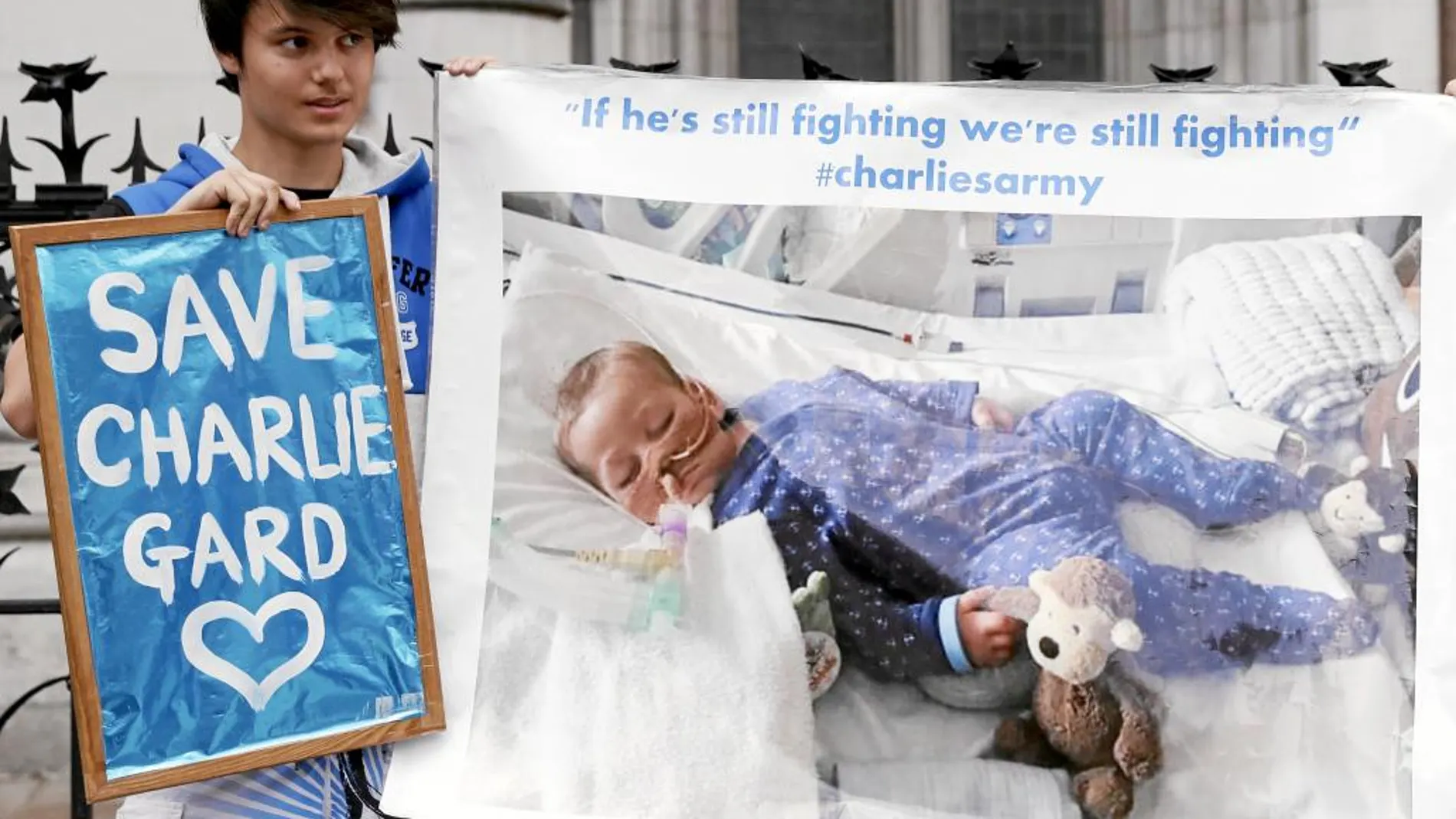 Un joven sostiene una pancarta con la imagen del pequeño Charlie pidiendo que no se le desconecte