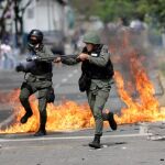 Miembros de la fuerza de seguridad antidisturbios de Venezuela apuntan con sus armas a manifestantes
