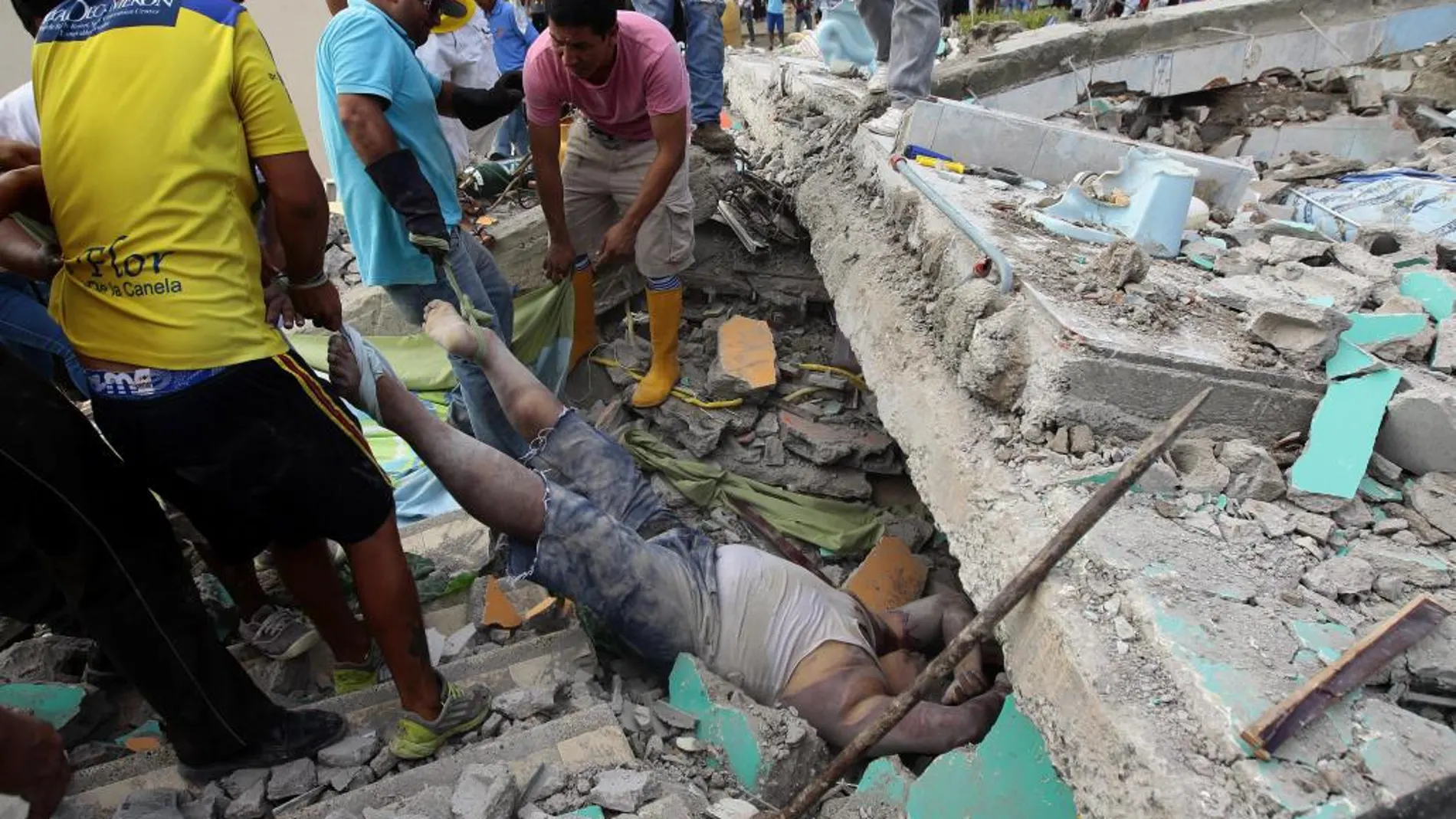 Unas personas rescatan un cuerpo entre los escombros en la localidad de Pedernales (Ecuador).