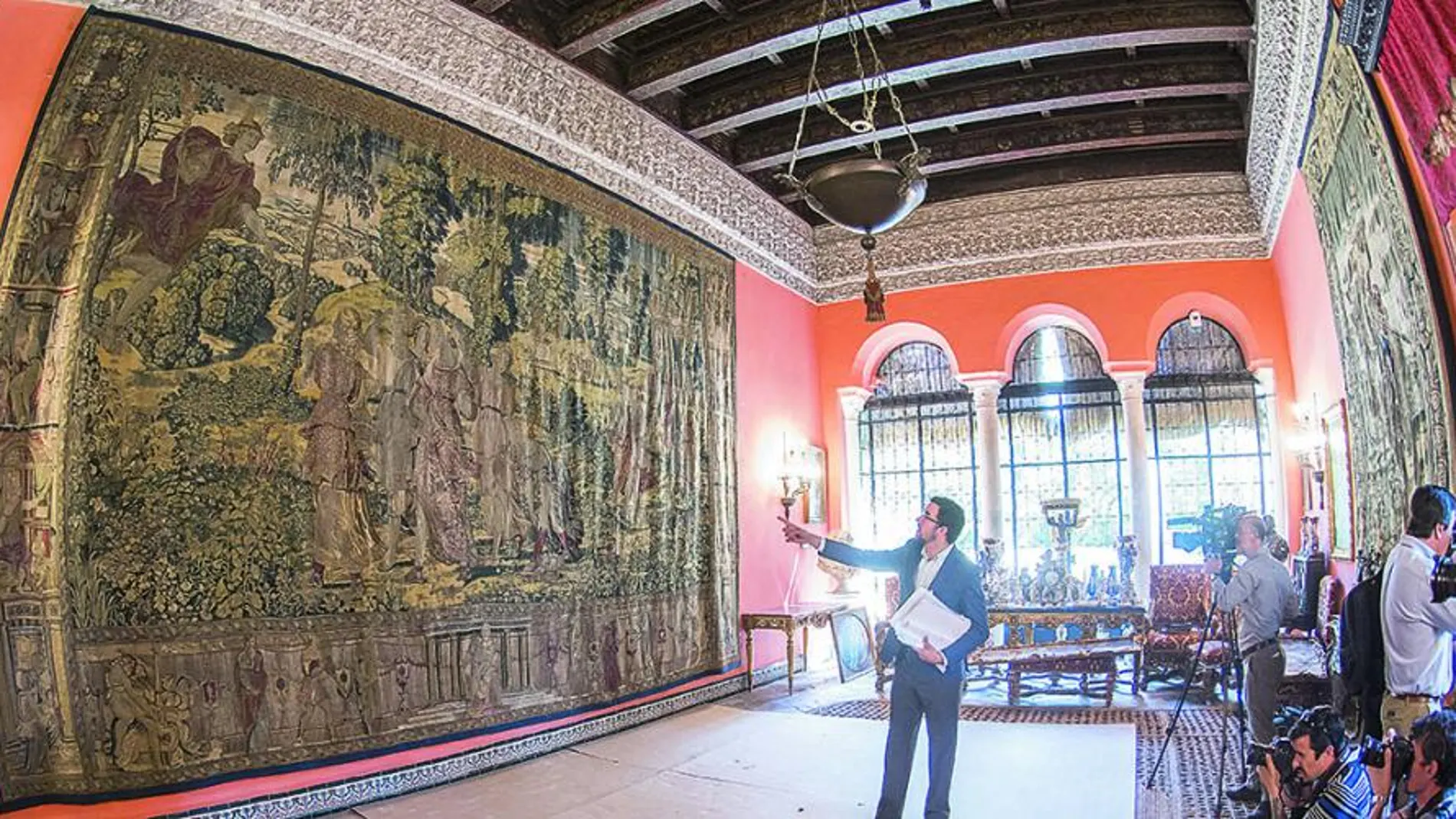 El gerente del Palacio de Las Dueñas explica a los periodistas la composición del tapiz