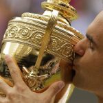 Roger Federer besa el trofeo que le acredita como campeón del torneo de Wimbledon.