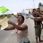 Vecinos piden comida y agua a los vehículos que pasan por una carretera en San Alejo, (Ecuador) ayer. Miles de ecuatorianos se han quedado sin alimentos y sin agua a la espera de la llegada de ayuda humanitaria