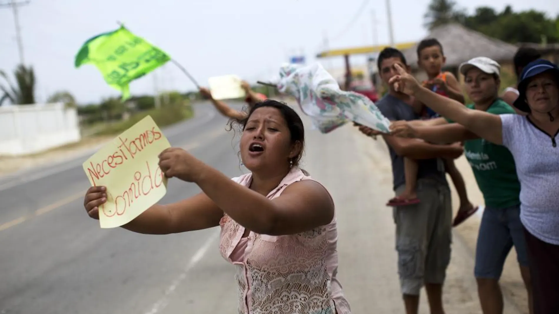 Vecinos piden comida y agua a los vehículos que pasan por una carretera en San Alejo, (Ecuador) ayer. Miles de ecuatorianos se han quedado sin alimentos y sin agua a la espera de la llegada de ayuda humanitaria