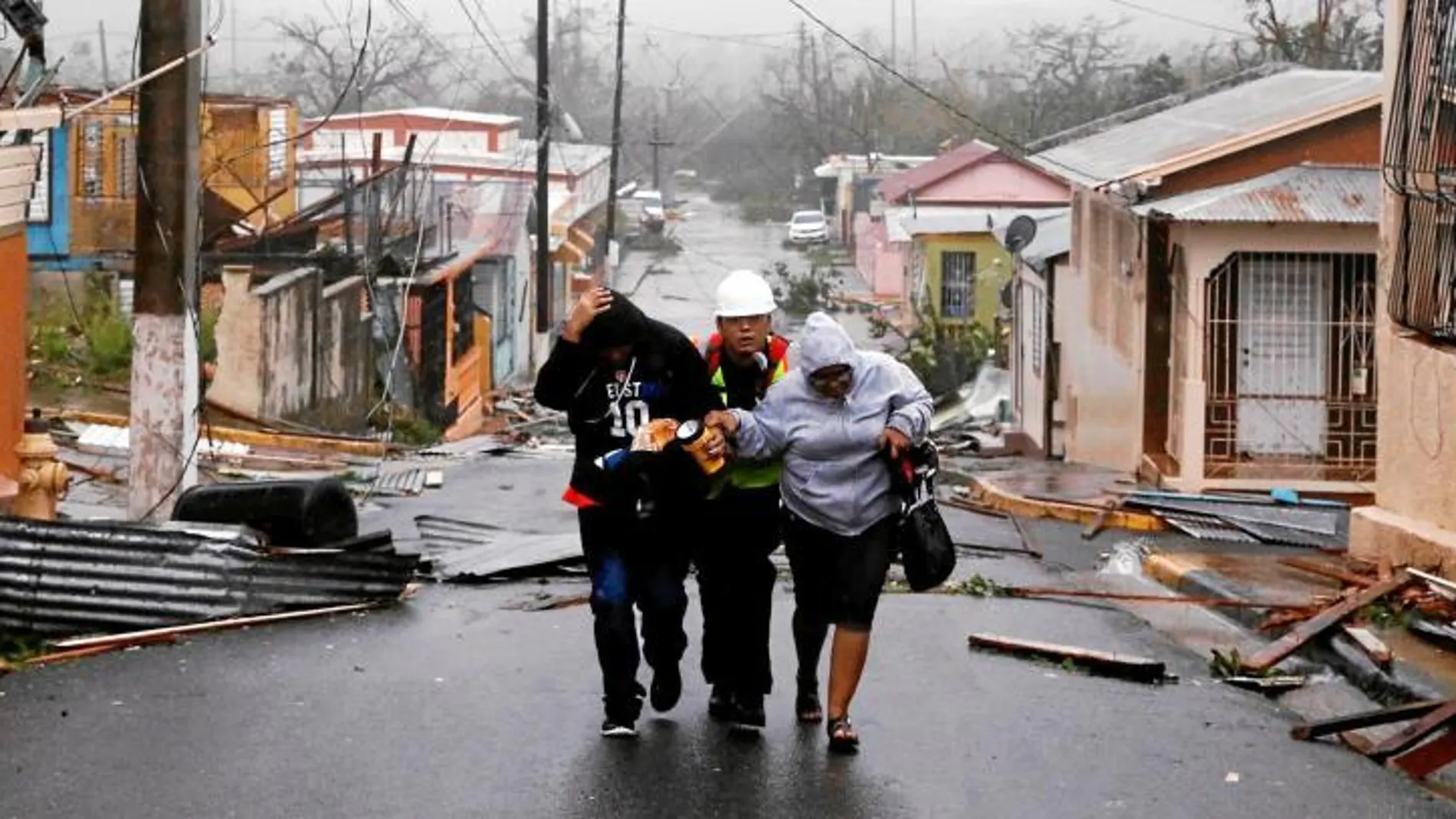Un miembro de los equipos de rescate ayuda ayer a unos vecinos de Guayama, en Puerto Rico
