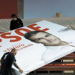 Tres operarios retiran un cartel electoral de Sánchez, tras un mitin 