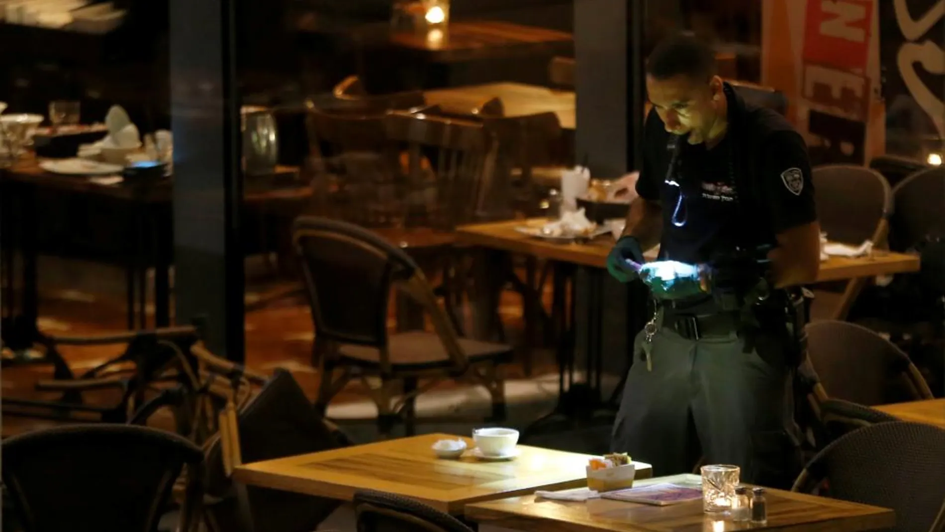 Un policía israel investiga en una cafetería del centro comercial