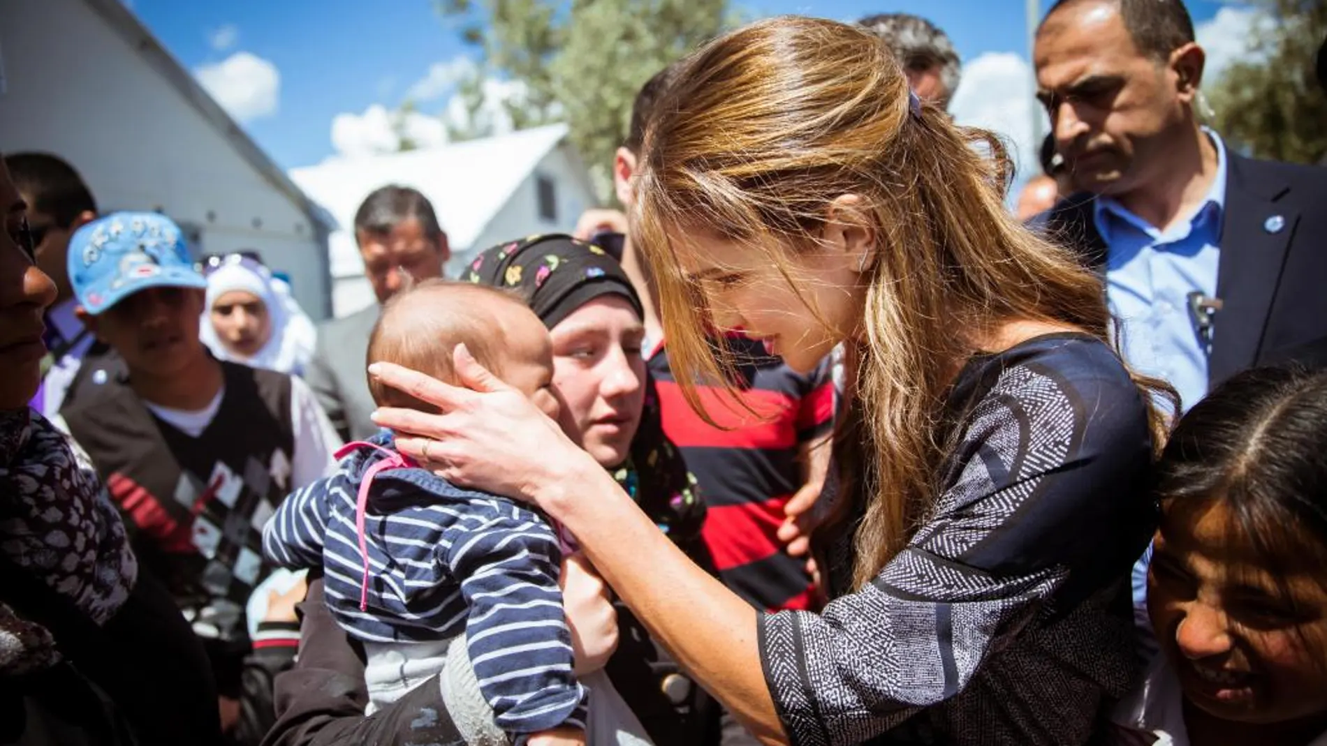 La reina de Jordania acaricia a un bebé durante su visita al compo de refugiados de Kara Tepe, en Lesbos