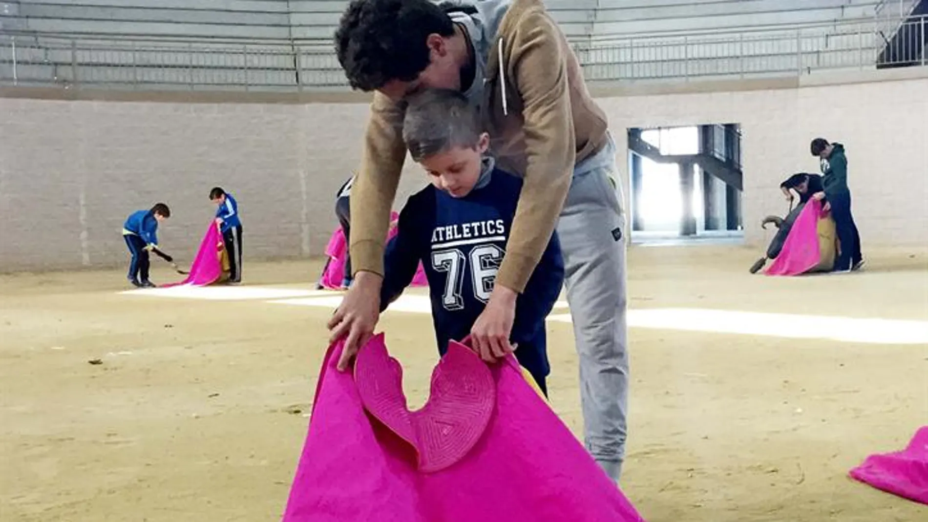 Ginés Marín enseña a uno de los niños a torear con el capote