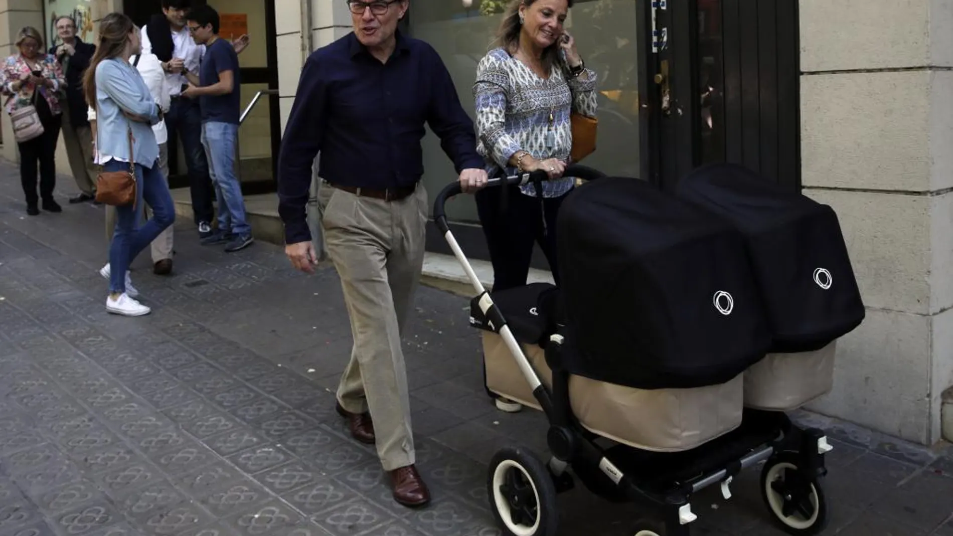 El presidente de CDC, Artur Mas, junto a su esposa, Helena Rakòsnik (d), y el carrito de sus dos nietas, tras votar