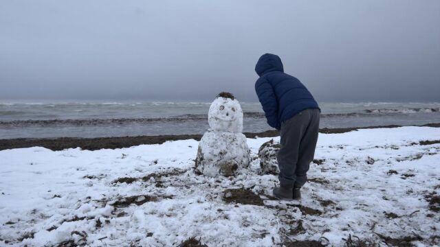 Un hombre hace un muñeco de nieve. Imagen de archivo