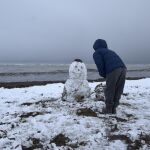 Un hombre hace un muñeco de nieve en la playa de Denia