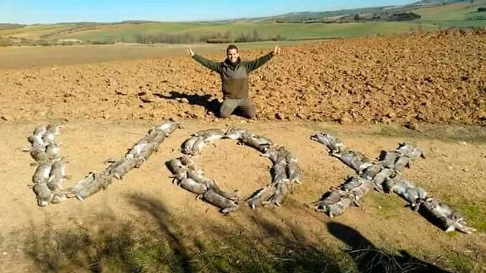 Un cazador con decenas de conejos muertos formando la palabra "Vox"