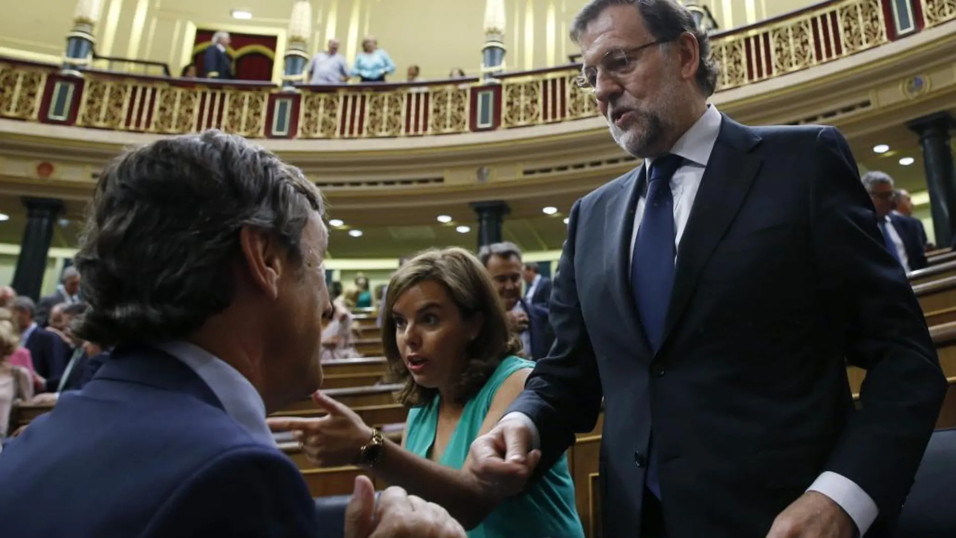 Rajoy (d), conversa con el portavoz parlamentario del PP, Rafael Hernando (i), en presencia de la vicepresidenta, Soraya Sáenz de Santamaría, en una foto de archivo