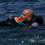 Un refugiado sirio nada con su bebé hacia la orilla de la isla de Lesbos