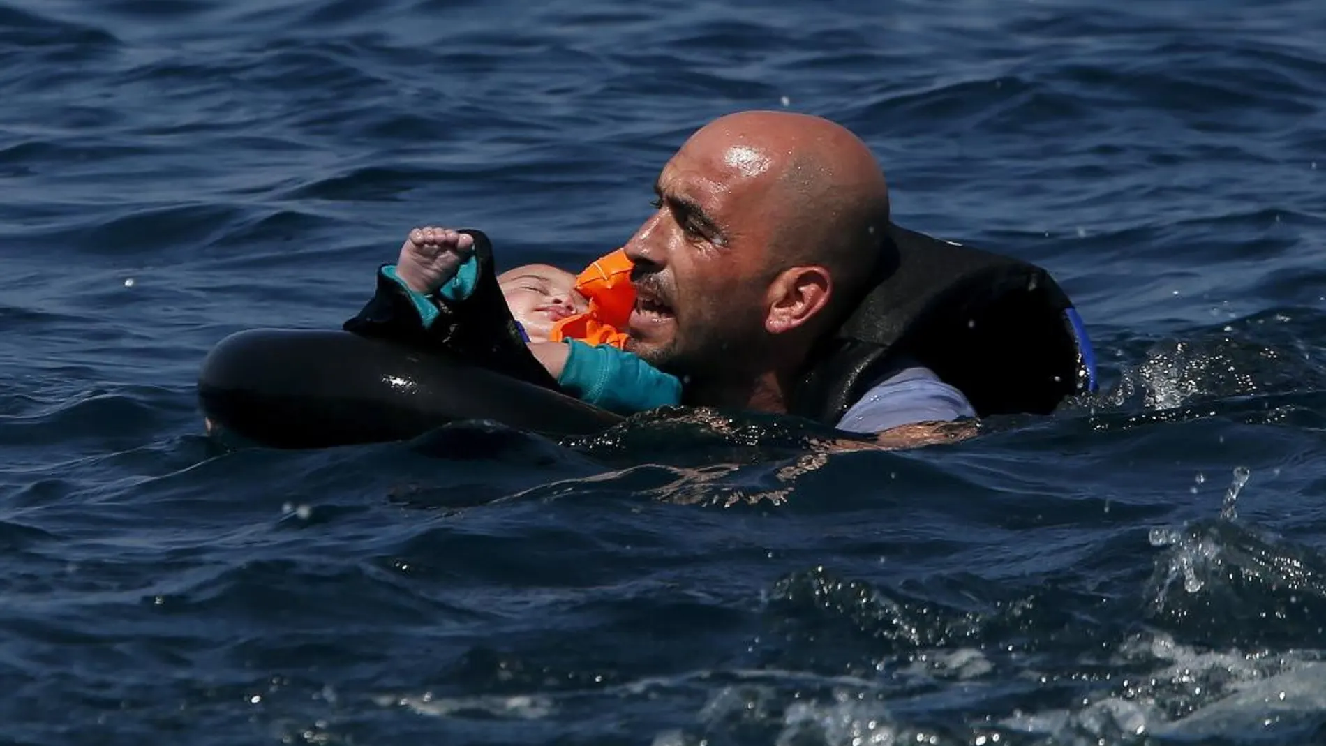 Un refugiado sirio nada con su bebé hacia la orilla de la isla de Lesbos