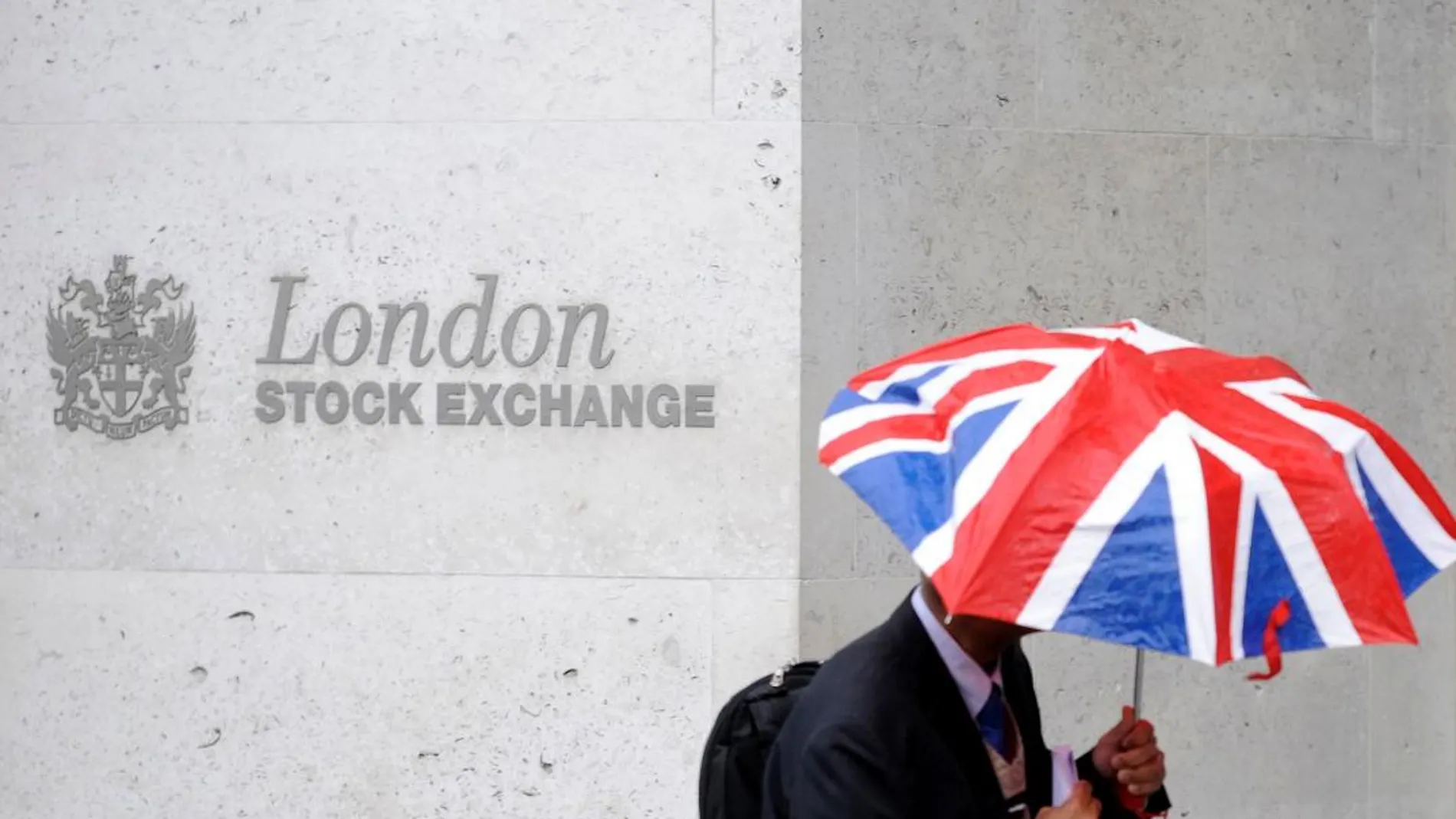 Un hombre con un paraguas con la bandera británica pasa junto a la sede de la bolsa de Londres. REUTERS/Toby Melville/Files