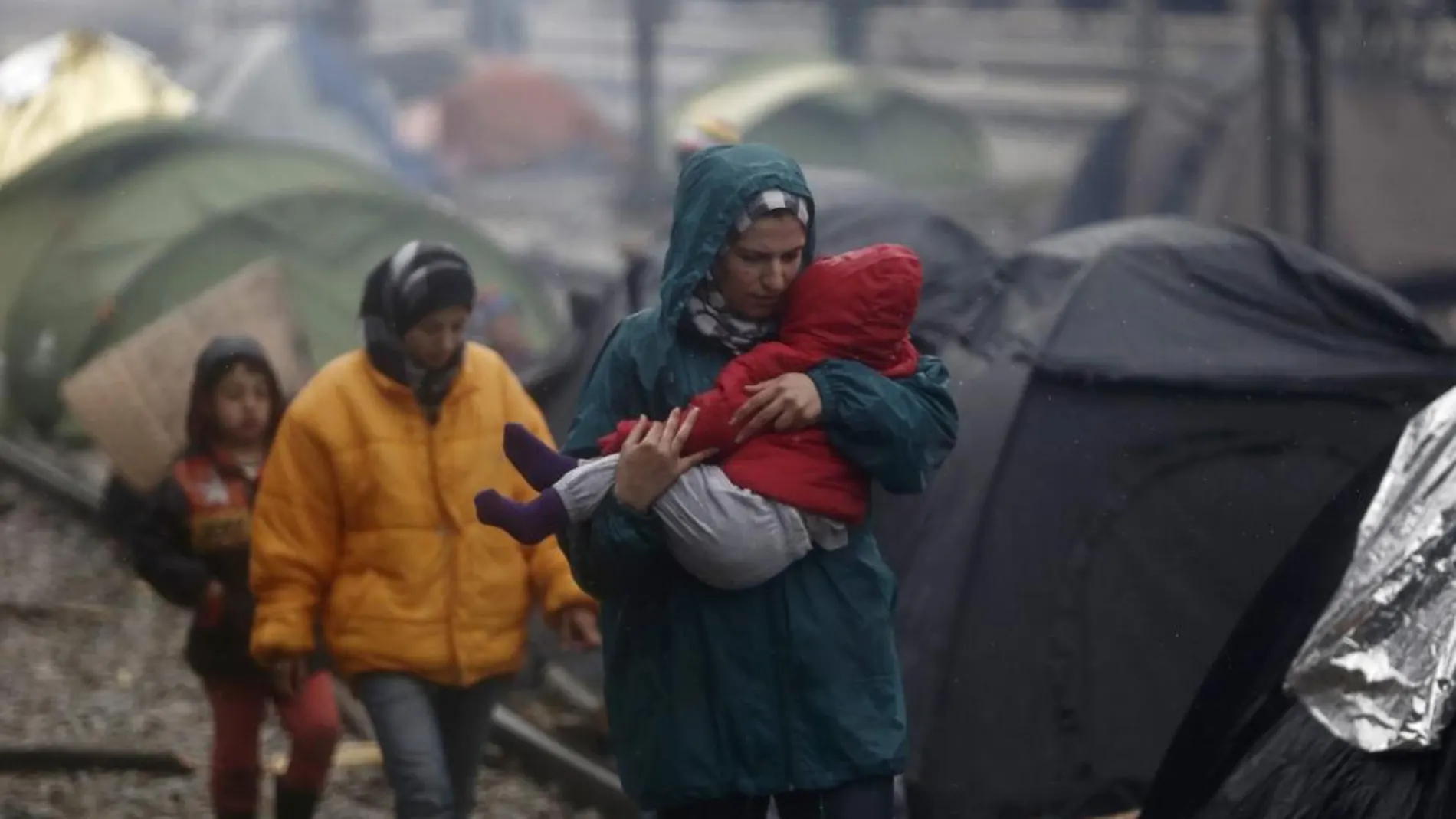 Una familia de refugiados espera en un campo de refugiados cerca de Idomeni (Grecia) para cruzar la frontera con Macedonia