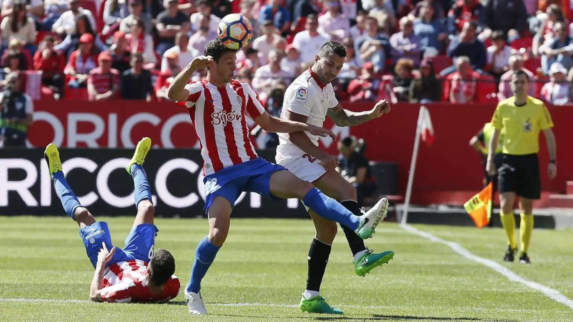 El jugador del Sporting de Gijón Mikel Vesga (c) disputa un balón con el centrocampista del Sevilla Víctor Machín 'Vitolo'