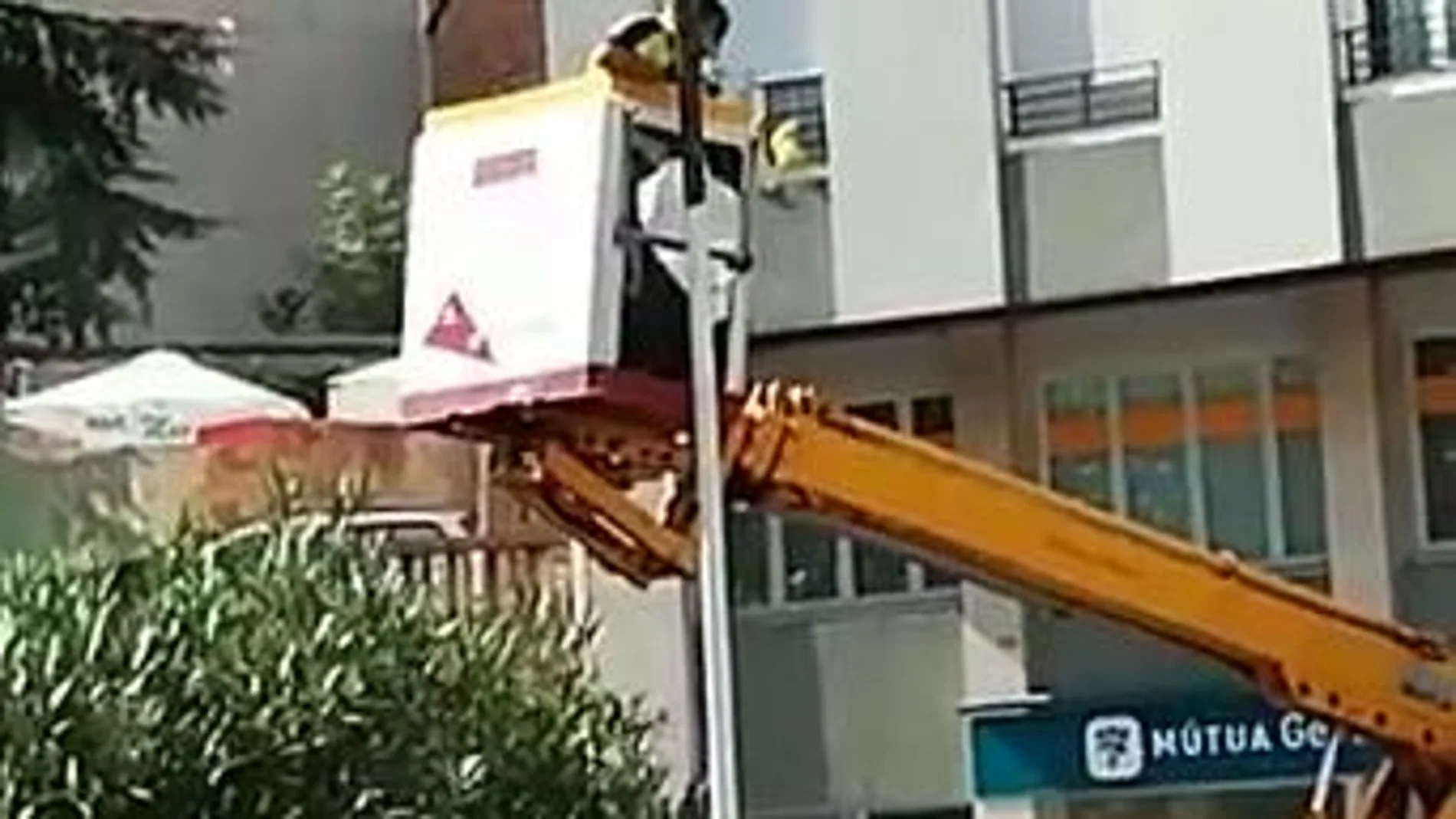 Un operario subido a una grúa del Ayuntamiento, engrasa el mástil del que cuelga una estelada