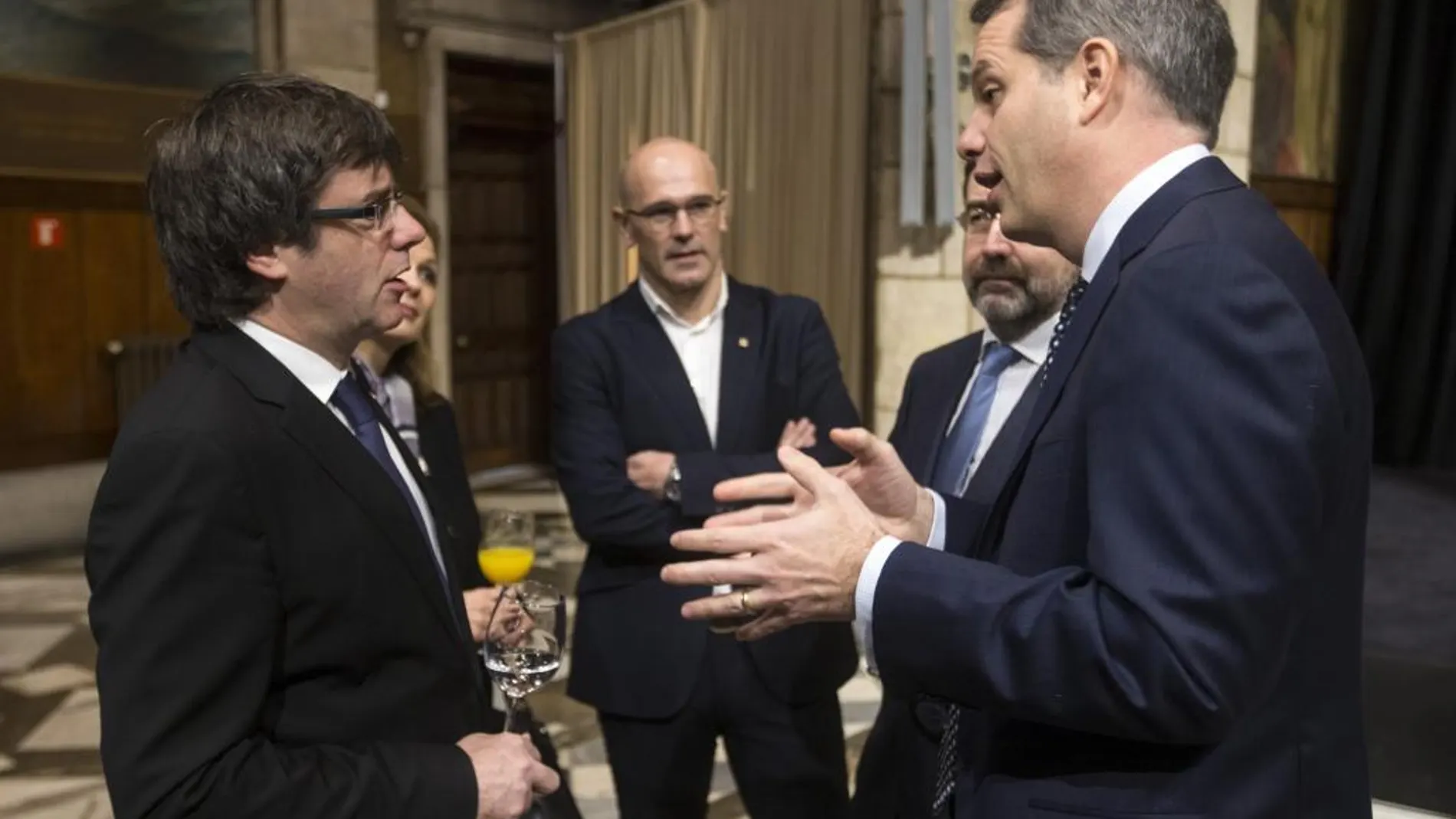 Puigdemont, acompañado del conseller de Exteriores, Raül Romeva , habla con el cónsul general de los Estados Unidos en Barcelona, Marcos Mandojana.