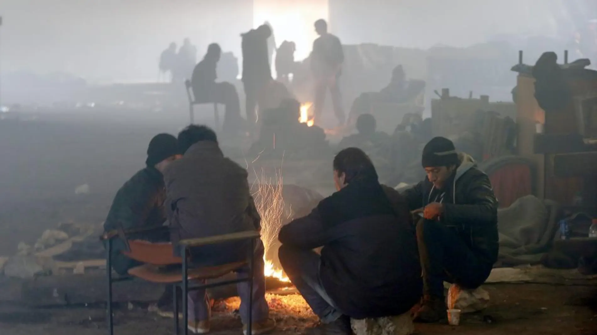 Varios refugiados se calientan junto a una hoguera en Belgrado ante las bajas temperaturas que sufre Europa.