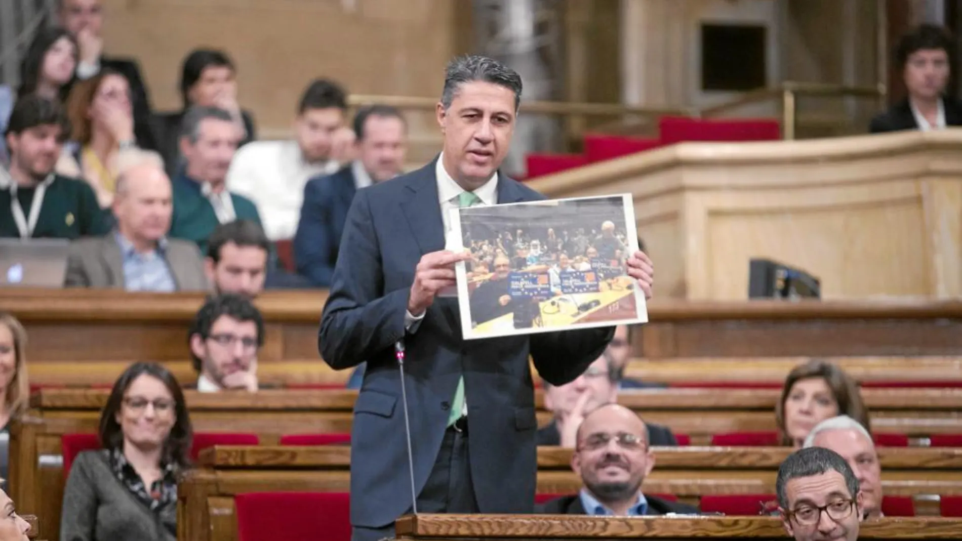 García Albiol, ayer en el Parlament,mostrando una fotografía del acto del Govern en una sala del Europarlamento con simpatizantes independentistas.