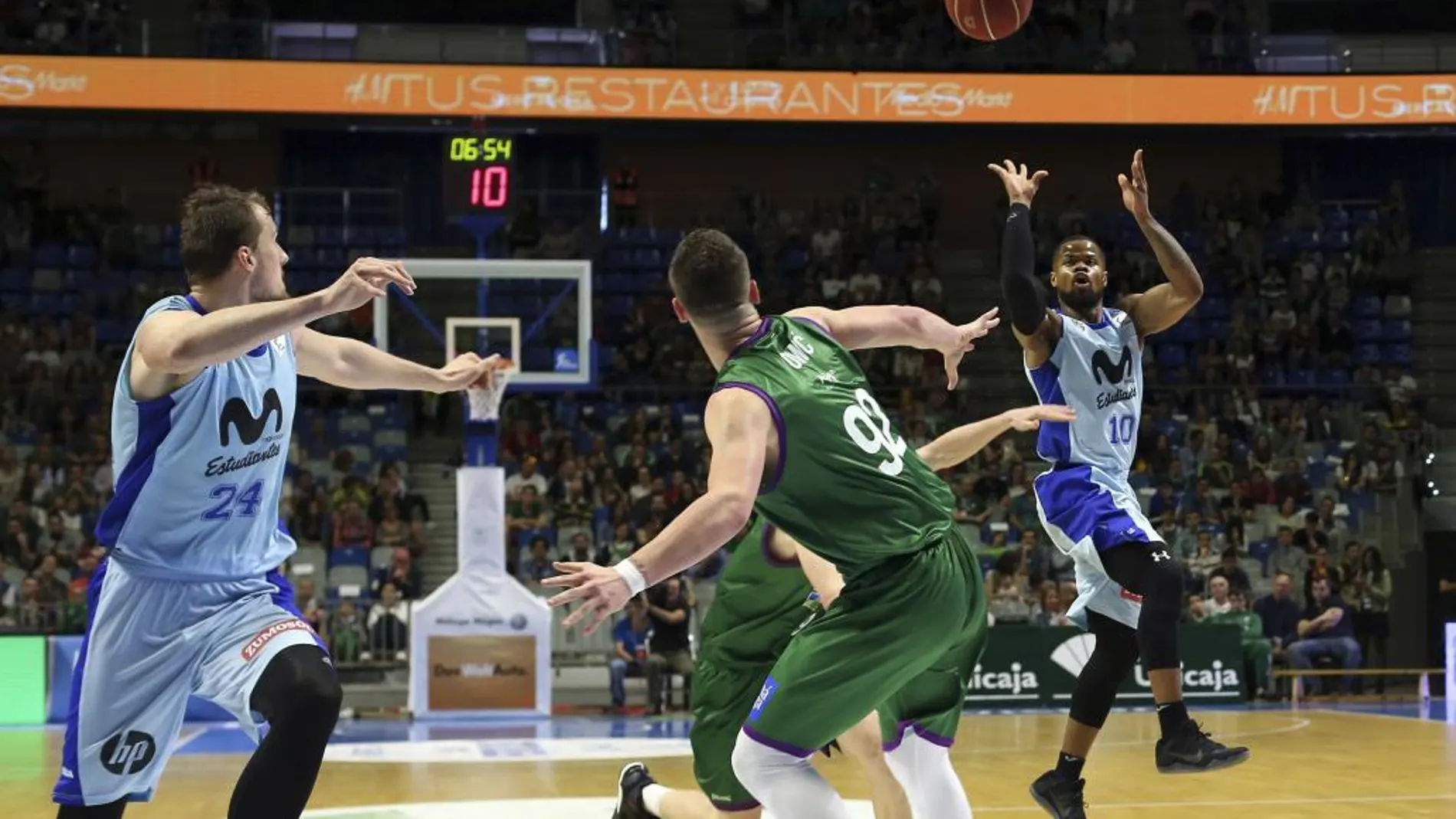 El base estadounidense del Movistar Estudiantes Omar Cook (d) realiza un pase a su compañero Ondrej Balvin (i) ante el jugador del Unicaja Alen Omic (c).