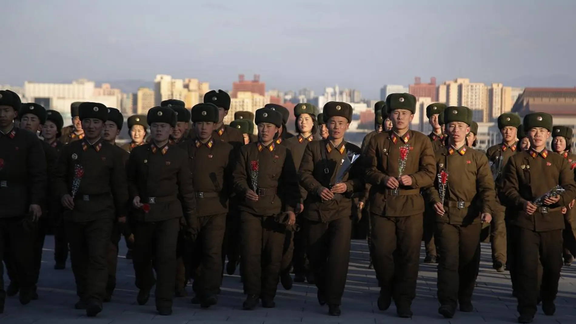 Militares norcoreanos ofrecen flores frente a las estatuas de bronce de Kim Il Sung y Kim Jong Il