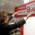Una empleada de un gran comercio coloca un cartel de artículos rebajados hoy en Madrid.