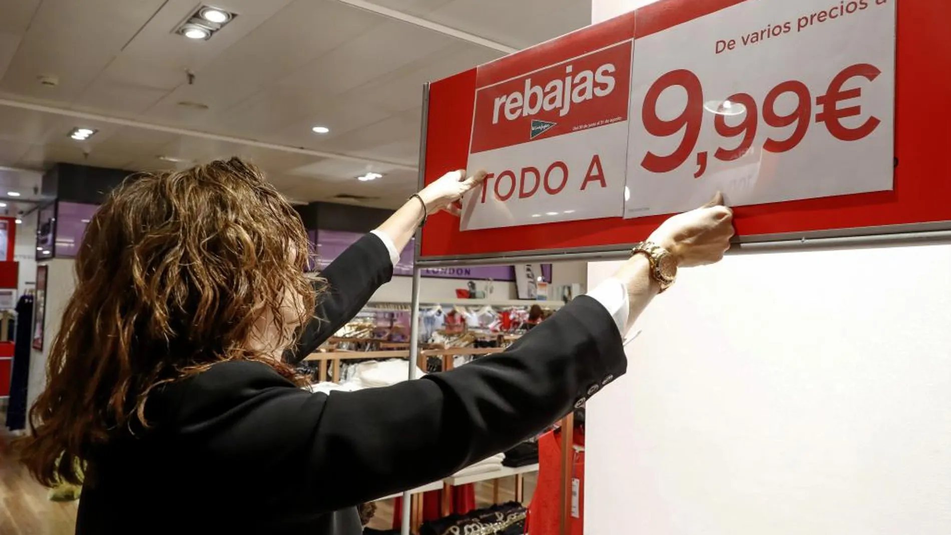 Una empleada de un gran comercio coloca un cartel de artículos rebajados hoy en Madrid.